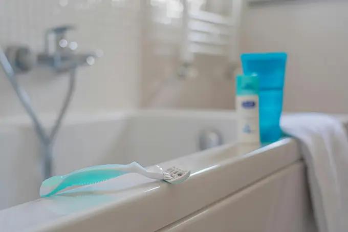 Close-up of a Venus razor with a chrome handle on a bathtub edge