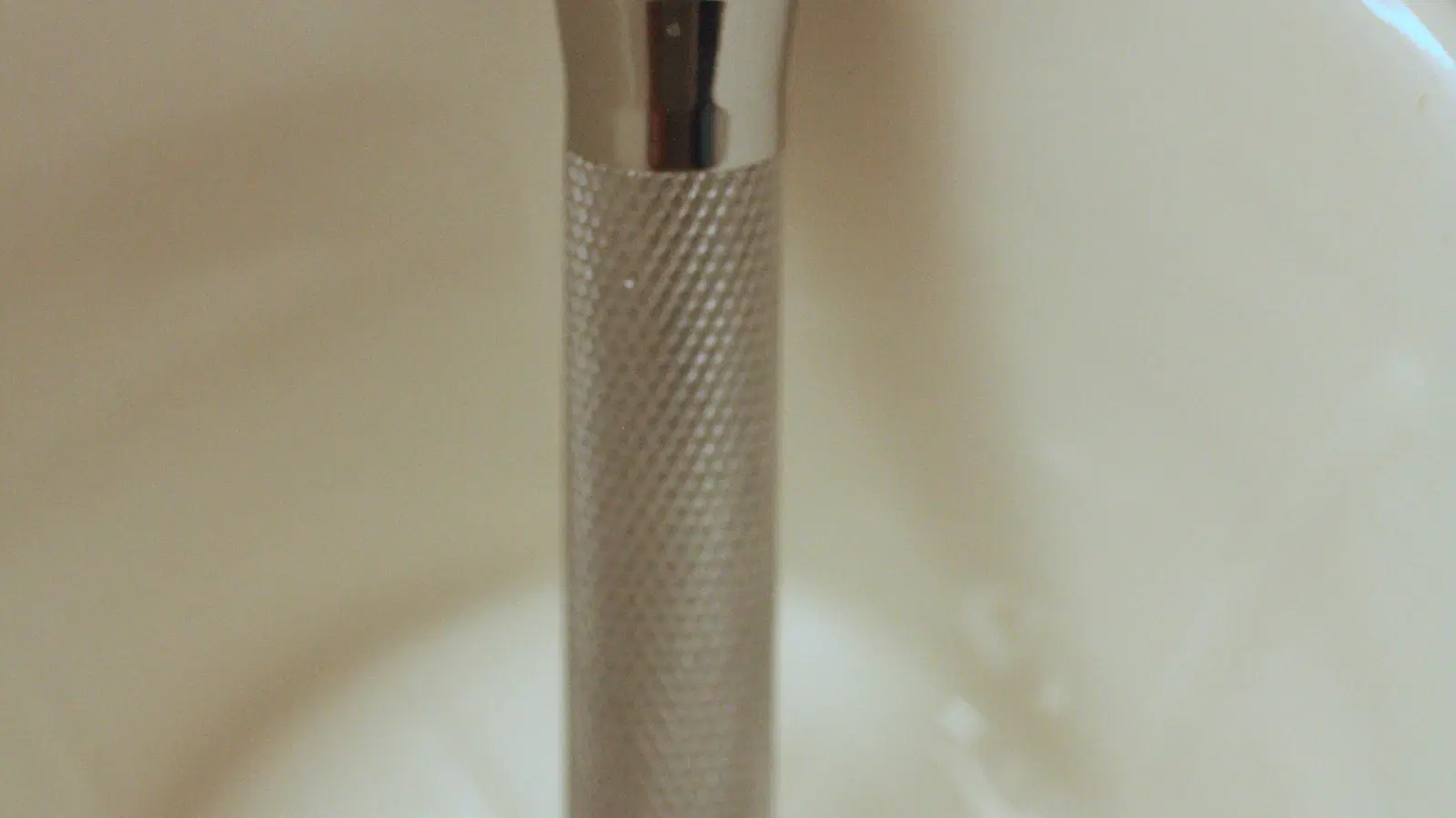 Cremo shave cream being applied to the pubic area — clear gel formula visible on skin, no foam, razor tracking its path