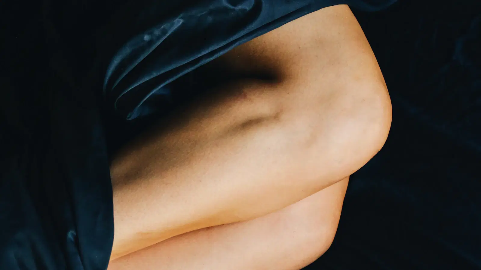 Femboy shaving legs in the shower — razor held flat against the skin, downward stroke with the grain on a fully lathered leg