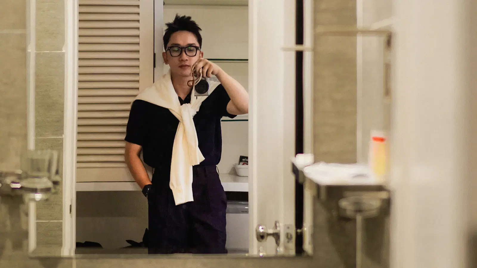 Flat-lay of men's pubic shaving gear — bikini trimmer, pivot-head razor, fragrance-free body wash, salicylic toner, and a clean towel