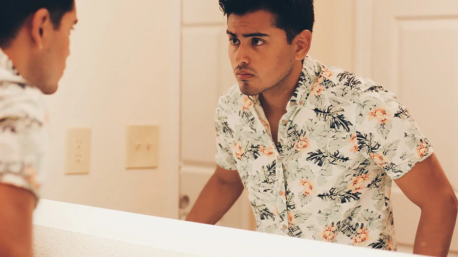 How to shave your butt — femboy-specific method with bikini razor, slip-heavy cream, hand mirror, and post-shave serum laid out on a pink-lit bathroom counter