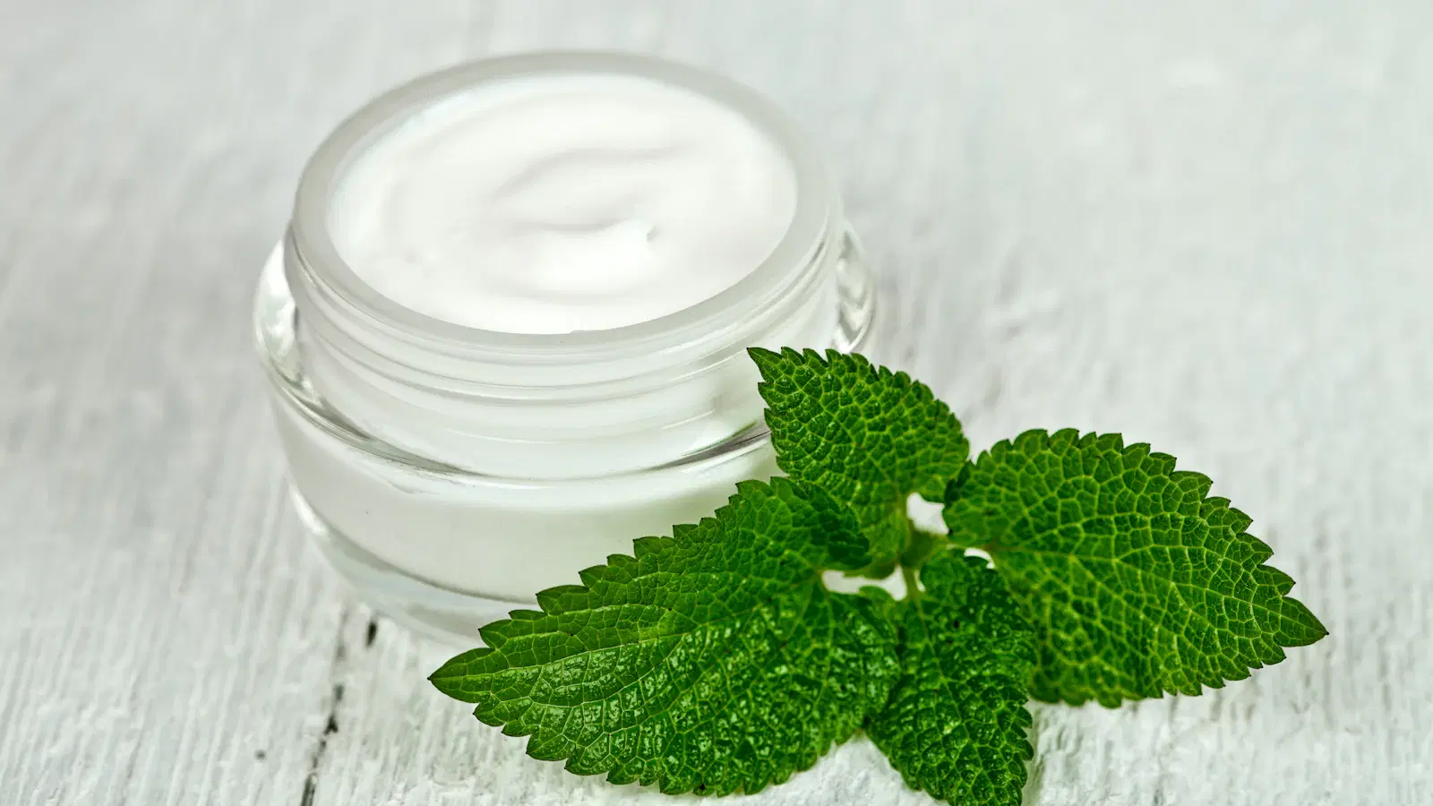 Proper bikini trimmer angle for shaving around the anus — guard flat to skin, hand spreading the cheek, slow outward strokes